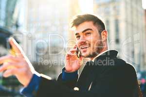 Taxi please. a cheerful young man talking on his phone while waiting for a taxi to take him to work in the morning.