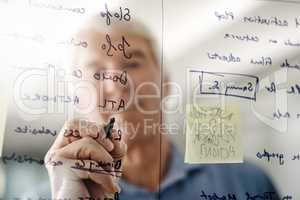 Its always good to see your ideas written down. a senior businessman writing down ideas with a pen marker on a glass wall in the office.