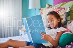 Books open magical new worlds for kids. an adorable little girl reading a book at home.