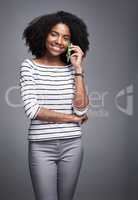 Answer every call of happiness. Studio portrait of a young woman using a mobile phone against a gray background.