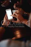 Lets invite more friends. Closeup of an unrecognizable man texting on his phone while being seated inside of a bar at night.