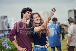 Slip in for a selfie. two cheerful young friends taking a self portrait together with a mobile phone outside during the day.