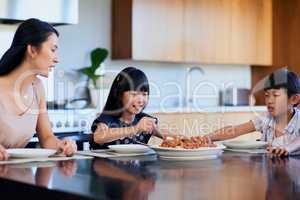 Mom made our favourite meal. two little children enjoying a meal with their mother at home.