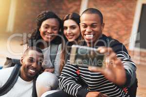 Gather round, its selfie time. a group of students taking selfies together on campus.