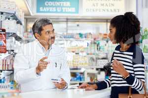 Explaining the dosage instructions. a pharmacist assisting a young woman in a chemist.