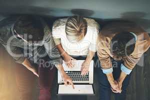 A group of planning, researching and professional business people working together on a laptop while sitting on the floor top view. A team of designers searching the web or completing a project