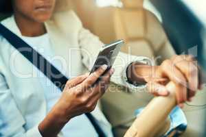 Looks like Im in for a surprise in the office. an unrecognizable businesswoman browsing on her mobile phone while driving in a car during the day.