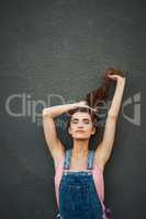 Lean back and take it easy. Portrait of a carefree young woman holding her hair up while standing against a grey background.