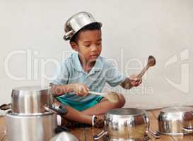 He wants to be a drummer when he grows up. an adorable little boy pretending to be a drummer with the pots at home.
