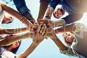 Sharing a solid friendship. Closeup shot of an unrecognizable group of people joining their hands in a huddle outdoors.
