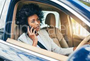 Traffic is holding me up. a cheerful young businesswoman driving in a car on her way to work while talking on a cellphone during the day.