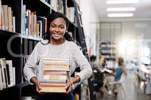 Plenty to read, plenty to learn. Portrait of a happy young woman carrying books in a library at college.