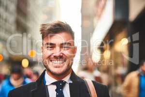Happy to be out and about in the city. Portrait of a cheerful young businessman standing in the middle of the busy streets of the city during morning hours.