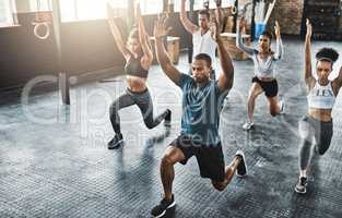 Workout with fitness minded people. a group of young people doing lunges together during their workout in a gym.