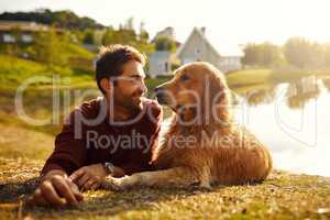 He couldnt have asked for a more loyal companion. Full length shot of a handsome young man and his dog spending the day by a lake in the park.