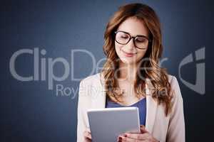 The convenient way of staying current. Studio shot of an attractive young businesswoman using a digital tablet against a dark blue background.