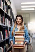 These are all the books Ill need this academic year. Portrait of a happy young woman carrying books in a library at college.