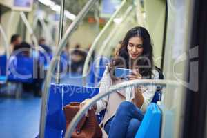 Staying entertained while commuting. a young attractive woman using a cellphone while commuting with the train.