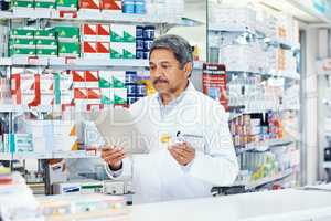 He always reads up further about the products in his dispensary. a mature pharmacist using a digital tablet in a chemist.