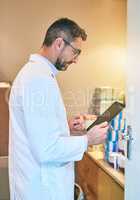 Pharmaceutical research is how he stays ahead of the competition. a mature man using a digital tablet in the back office of a pharmacy.