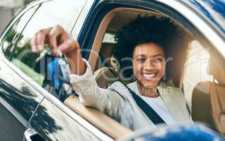 Would you like to drive. Portrait of a cheerful young woman driving in her car to work while holding a set of keys during the day.
