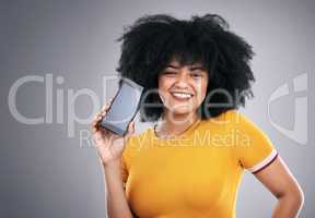 The perfect device to travel with. Studio shot of an attractive young woman posing with a cellphone against a grey background.