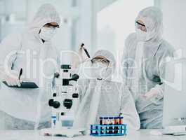 Group of doctors and scientists conducting medical research on viruses dressed in hazmat suits, for coronavirus cure in the lab. Researchers conducting experiments and examining test tube