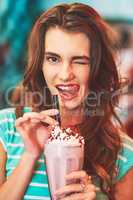 Mmmm now that was a yummy milkshake. a beautiful young woman drinking a milkshake in a diner.