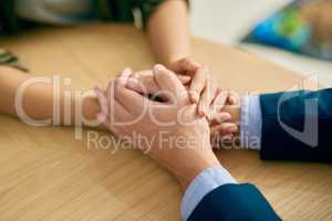 Compassion, the heart of humanity. a businessman and businesswoman compassionately holding hands at a table.