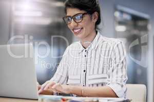 En route towards her next big success. a confident young businesswoman working on a laptop in an office.
