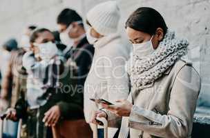 People or tourists traveling during covid and standing in line at a public travel facility wearing protective masks. Woman in a queue reading social media news about coronavirus pandemic on her phone