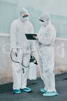 Healthcare workers cleaning outside a building using a list to follow instructions on biohazard safety during covid. Medical researchers wearing hazmat suits sanitizing outdoor to prevent infections