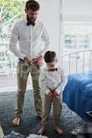 Making sure we dressed to perfection. an adorable little boy and his father getting dressed in matching outfits.