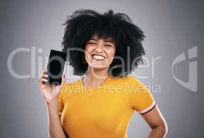 Connectivity on the go with this device. Studio shot of an attractive young woman posing with a cellphone against a grey background.