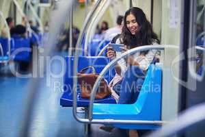 She can binge on shows while commuting. a young attractive woman using a cellphone while commuting with the train.