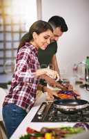 We fell in love through cooking. a young attractive couple cooking together in the kitchen at home.