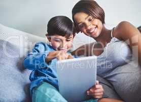 Using the internet to educate him about babies. an adorable little boy and his pregnant mother using a laptop while relaxing on her bed.