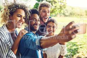 Smile everyone. a group of friends taking a selfie together outdoors.