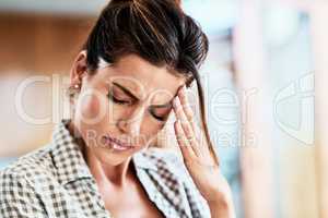 Oh this is a terrible migraine. an attractive young woman suffering with a headache at home.