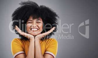 Her smile is effervescent. Studio shot of an attractive young woman posing against a grey background.