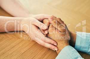 Nothing heals like the human touch. a man and woman holding hands in comfort on a table.
