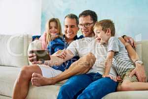 Family fun. an affectionate family of four taking selfies on the sofa at home.