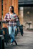 Enjoying being a student. a young female student holding textbooks outside on campus.