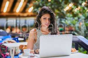 At the cafe with the fastest wifi. an attractive young woman using a laptop at a cafe.