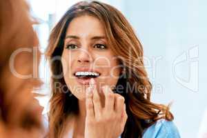 Creating the perfect pout. a beautiful young woman grooming herself at home.