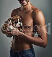 Sexy guy, cute puppy...perfection. Studio shot of a handsome and shirtless young man holding a bulldog puppy against a grey background.