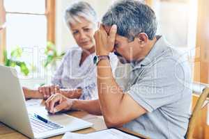 When debt becomes a reality. a mature couple looking stressed out while managing their paperwork together at home.