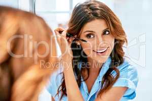 Enhancing her beautiful eyes with some mascara. a beautiful young woman applying mascara to her lashes at home.