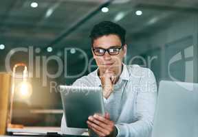 I will need to give this some more thought. a handsome young businessman using a digital tablet in an office at night.