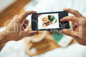 Food for thought and food for my tummy. High angle shot of an unrecognizable man taking a picture of his breakfast in bed at home.